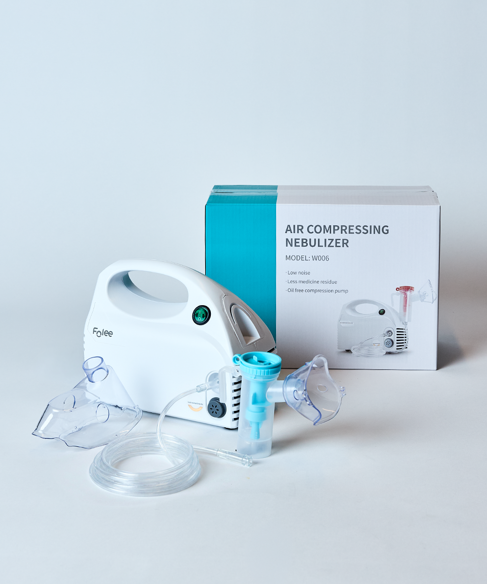 A Foyou air compressing nebulizer set with a white handheld unit, clear tubing, two clear face masks, and its retail box on a clean white background.